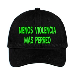 Op de afbeelding: Zwarte baseballpet met groene geborduurde tekst die "MENOS VIOLENCIA MÁS PERREO" luidt.