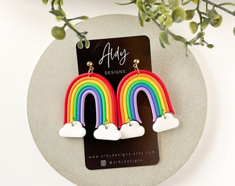 Könnte beinhalten: Regenbogen- und Wolkenohrringe mit goldenen Haken. Die Ohrringe befinden sich auf einer weißen Karte mit dem Text "Aldy Designs" und der Website-Adresse "www.aldydesigns.etsy.com".