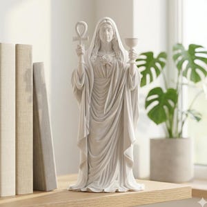 May include: A white statue of a robed figure holding an ankh and a chalice. The statue has long hair and a rose on the chest. The statue is on a wooden shelf with books to the left and a potted plant in the background.
