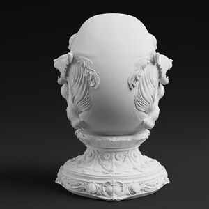 Peut inclure: Une sculpture d&eacute;corative en forme d'&oelig;uf blanc mat pr&eacute;sentant des sculptures en relief complexes de t&ecirc;tes de lion rugissantes sur les c&ocirc;t&eacute;s. L'objet repose sur un large socle orn&eacute; d&eacute;cor&eacute; de motifs floraux et de volutes d&eacute;taill&eacute;s sur l'ensemble.