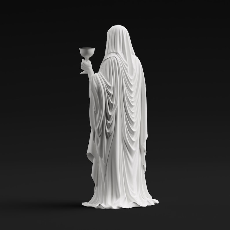 May include: A white statue of a figure draped in a long, flowing hooded robe, viewed from behind. The figure holds a small, stemmed chalice in one hand. The sculpture features intricate, deep folds in the fabric that cascade down to the base.