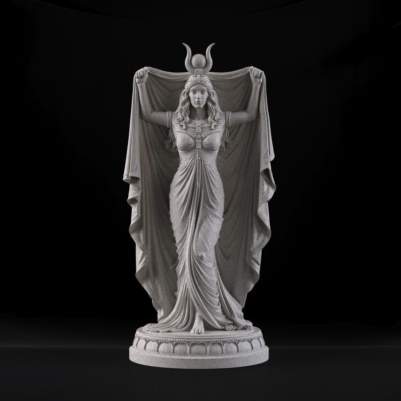Peut inclure: Une statue gris clair couleur pierre repr&eacute;sentant une silhouette debout aux longs cheveux, v&ecirc;tue d'une longue robe drap&eacute;e et d'une coiffe orn&eacute;e d'un croissant de lune et d'une sph&egrave;re centrale. La silhouette tient un grand tissu d&eacute;ploy&eacute;.