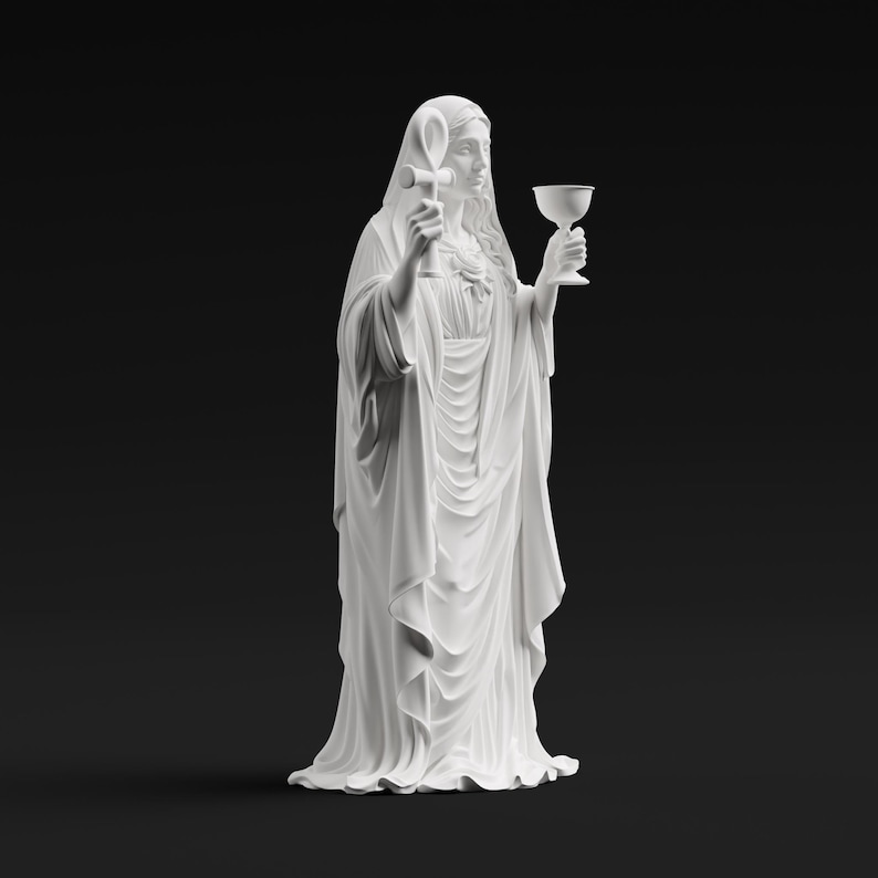 May include: A matte white statue of a figure draped in flowing robes, holding an ankh symbol in the right hand and a chalice in the left hand. The figure has long hair and a veil, with a heart emblem visible on the chest area of the garment.