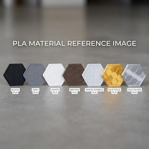 May include: A PLA material reference image featuring seven hexagonal tiles in a row. The colors are labeled as black, grey, white, brown, white marble, silk gold, and silk silver. Each tile displays a raised honeycomb pattern on its surface.