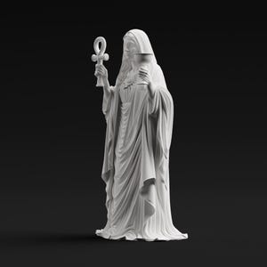 May include: A matte white statue of a robed figure with a hooded head, holding an ankh symbol in the right hand and a chalice in the left hand. The figure wears a long, flowing garment with detailed vertical folds and drapes throughout the fabric.