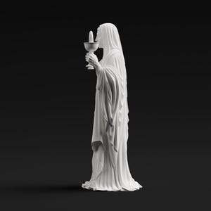 May include: A white matte statue of a figure draped in long, flowing robes, standing in profile. The figure holds a chalice with a small, upright cylindrical object inside. The sculpture features detailed folds in the fabric and a smooth finish.