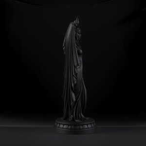 Peut inclure: Une sculpture noir mat repr&eacute;sentant une silhouette debout de profil, drap&eacute;e dans un tissu long et fluide qui recouvre la t&ecirc;te. La figurine est plac&eacute;e sur une base circulaire &agrave; gradins avec un motif d&eacute;coratif r&eacute;p&eacute;t&eacute; sur le bord inf&eacute;rieur.