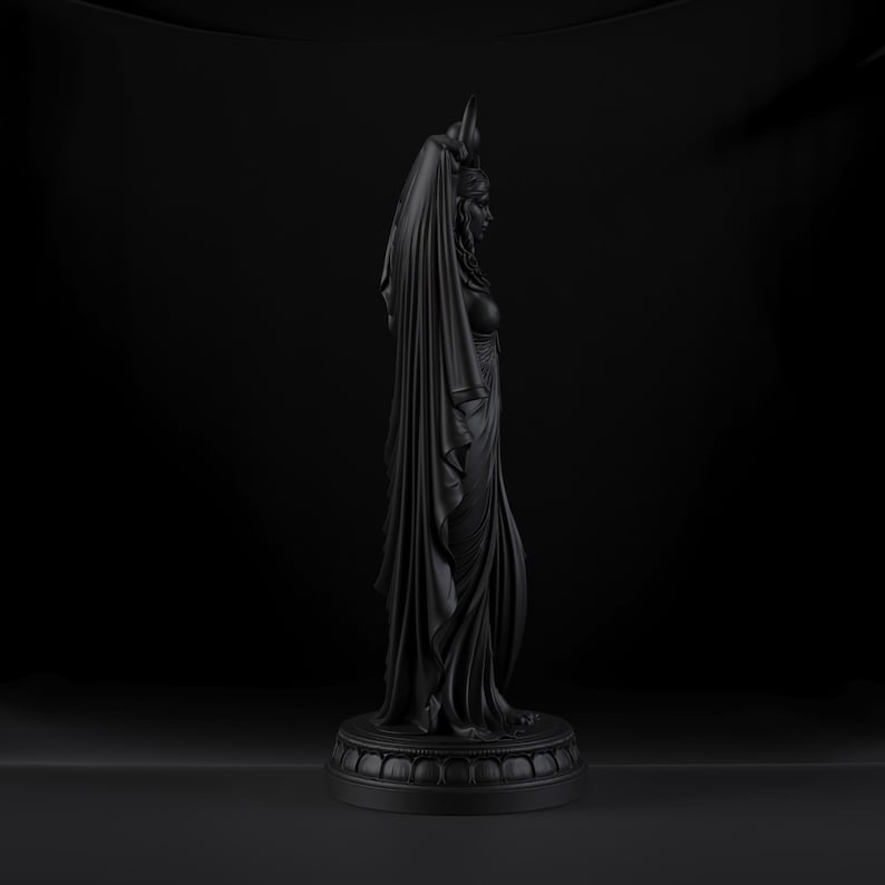 Peut inclure: Une sculpture noir mat repr&eacute;sentant une silhouette debout de profil, drap&eacute;e dans un tissu long et fluide qui recouvre la t&ecirc;te. La figurine est plac&eacute;e sur une base circulaire &agrave; gradins avec un motif d&eacute;coratif r&eacute;p&eacute;t&eacute; sur le bord inf&eacute;rieur.