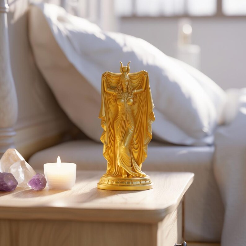 Peut inclure: Une figurine dor&eacute;e repr&eacute;sentant une silhouette debout avec une coiffe en forme de croissant de lune, v&ecirc;tue d'une longue robe fluide, les bras lev&eacute;s tenant un tissu drap&eacute;. La statue pr&eacute;sente des plis complexes et repose sur une base circulaire.