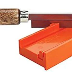 Puede incluir: Una sierra de inglete con mango de madera y hoja de metal. La sierra está en una caja de inglete de plástico naranja brillante.