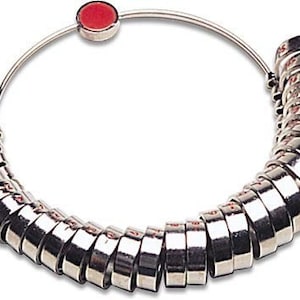 May include: A silver ring sizer with a red button. The sizer is made up of a series of graduated rings that are attached to a metal hoop.