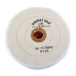 May include: A white buffing wheel with the text "GROBET USA" and "NO. 17.75802 5 X 20" printed on it. The wheel has a central brown and red core and is stitched around the edges.