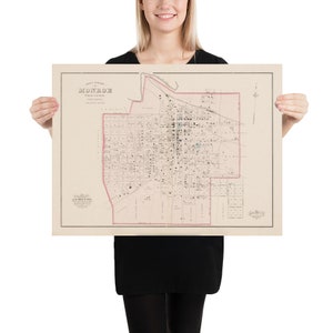 Peut inclure: Une carte vintage de Monroe, en Louisiane, imprimée en noir et blanc avec des accents rouges et bleus. La carte montre les rues, les bâtiments et les parcs de la ville. Le titre "Monroe, Louisiane" est imprimé en haut de la carte.