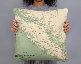 May include: A green and beige throw pillow with a vintage map of the southwestern part of British Columbia. The map shows the location of Rupert, District, Tancou, and New West. The text "MAP OF THE SOUTHWESTERN PART OF BRITISH COLUMBIA" is printed on the pillow.