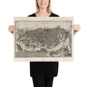 Puede incluir: Un mapa vintage en blanco y negro de Toledo, Espa&ntilde;a. El mapa muestra el dise&ntilde;o de la ciudad con calles, edificios y el paisaje circundante. El t&iacute;tulo "TOLETUM" est&aacute; impreso en la parte superior del mapa.