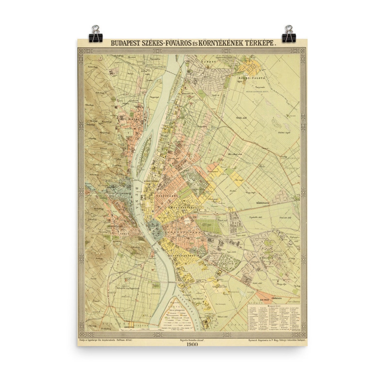 May include: A vintage map of Budapest, Hungary, from 1900. The map is in shades of yellow, green, and brown, with a river running through the center. The map is titled 'Budapest Szekes-Fovaros is Kornyekenek Terkepe.' The map shows the city's streets, parks, and buildings. The map is surrounded by a decorative border.
