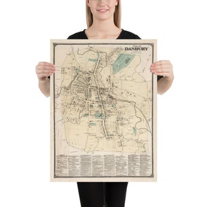 May include: A vintage map of Danbury, Connecticut, printed in black and white with some green accents. The map shows the layout of the city with streets, buildings, and landmarks. The title "Plan of Danbury" is printed at the top of the map.