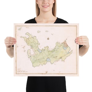 May include: A vintage map of the island of Saint Helena, printed on a cream-colored paper with a light brown border. The map is hand-drawn and features a green and brown color scheme. The map is surrounded by a white border.