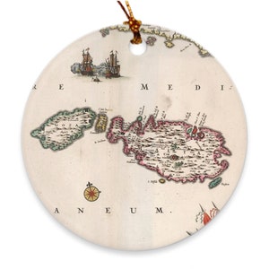 May include: An antique map of the island of Malta, with the surrounding islands of Gozo and Comino, printed on a round ceramic ornament. The map is in shades of pink, green, and brown, with text in a black font.