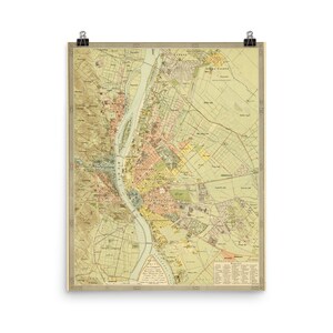 May include: A vintage map of Budapest, Hungary. The map is printed in shades of green, yellow, and brown. The Danube River is shown in blue, and the city is divided into districts. The map includes a key with the names of the districts and other features.
