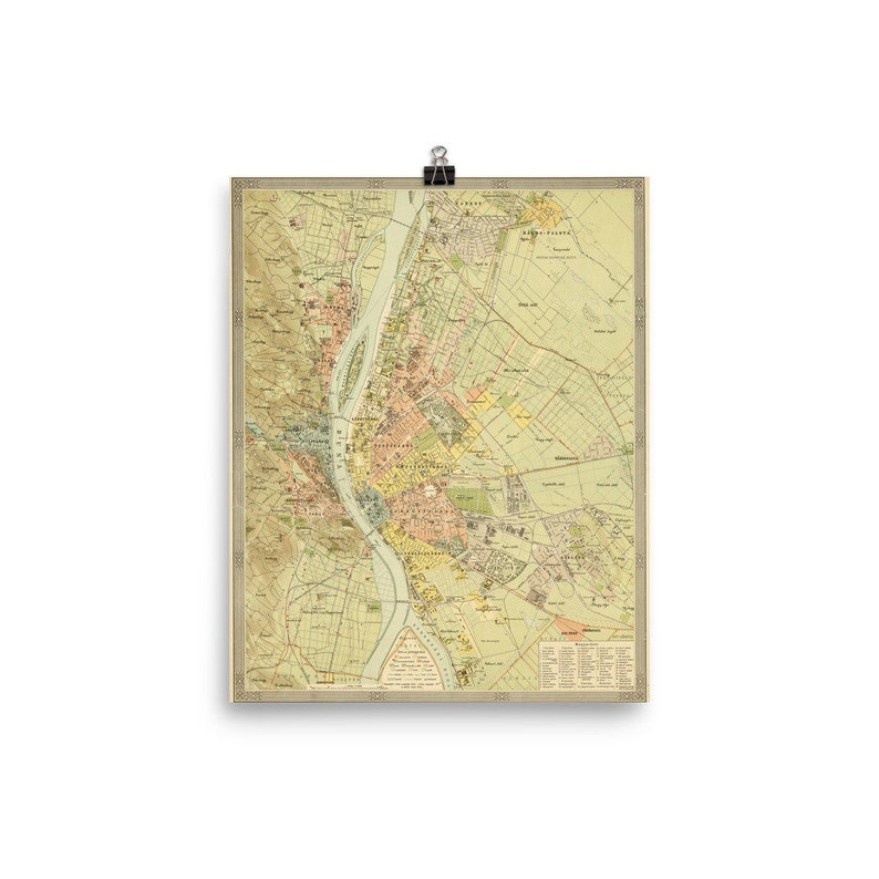 May include: A vintage map of Budapest, Hungary. The map is printed in shades of yellow, green, pink, and blue. The Danube River is shown in blue, and the city is divided into districts. The map includes text in German and Hungarian.