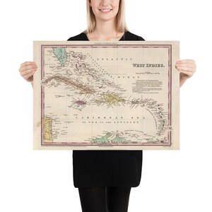 May include: An antique map of the West Indies, showing the islands of the Caribbean Sea. The map is printed in black, red, green, and yellow on a white background. The map is titled "West Indies" and includes the text "Caribbean Sea or Sea of the Antilles".