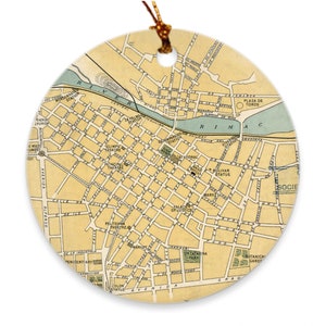 Puede incluir: Un mapa vintage de Lima, Perú, impreso en un adorno redondo de cerámica. El mapa muestra las calles de la ciudad, los puntos de referencia y el río Rímac. El adorno es de color beige claro con acentos marrones y verdes.