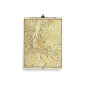 May include: A vintage map of Budapest, Hungary, printed in 1900. The map is in shades of yellow, green, and brown, with a blue river running through the center. The title of the map is 'Budapest Szekes-Fonal-Korneyenek Terkepe.'  The map shows the city's streets, parks, and other features.
