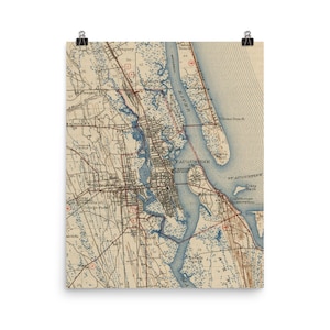May include: An antique map of St. Augustine, Florida, showing the city's streets, waterways, and surrounding areas. The map is printed in shades of brown, blue, and red, with text labels indicating various locations and features.