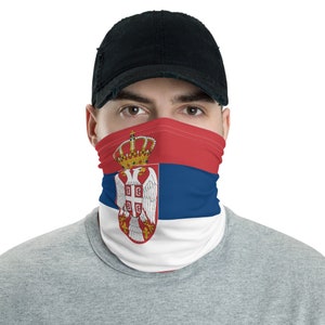 Pode incluir: Uma máscara facial com a bandeira da Sérvia. A máscara é vermelha, azul e branca com o brasão de armas sérvio no centro. A máscara é usada por uma pessoa com um boné de beisebol preto.