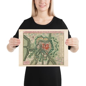 May include: A vintage map of Luxembourg City, printed on paper with a cream background. The map shows the city's layout with green and red details. The title "Nouveau Plan de la Ville de Luxembourg" is printed at the top of the map.