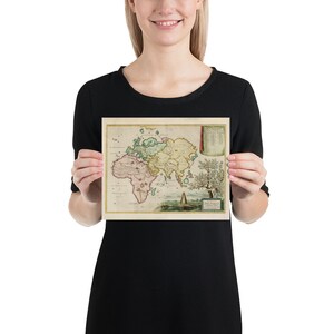 May include: A vintage world map print featuring a detailed illustration of the continents in shades of green, yellow, and pink. The map is surrounded by a decorative border and includes a key with labels in Latin.