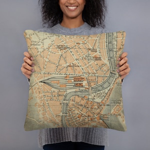 Peut inclure: Un coussin décoratif avec une carte vintage d'une ville avec une rivière qui la traverse. La carte est dans des tons de brun, orange et jaune. Le coussin est fait d'un tissu beige doux.