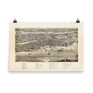 May include: A vintage black and white print of St. Augustine, Florida, from 1884. The print shows a detailed aerial view of the city, with buildings, boats, and a lighthouse. The print is held by two black binder clips.