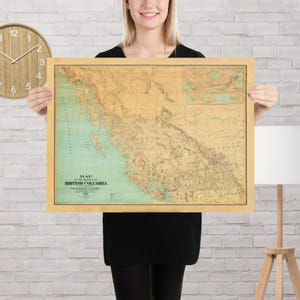 May include: A framed vintage map of British Columbia, Canada, with a beige border. The map features shades of tan, green, and blue, depicting the province's geography. The title "Map of the Province of British Columbia" is visible.