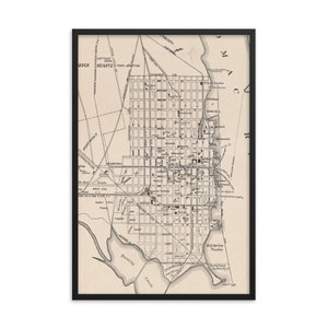 May include: A vintage black and white map of the city of Baltimore, Maryland. The map shows the city's streets, parks, and waterways. The map is framed in a black frame.