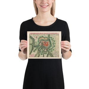 May include: A vintage map of the city of Luxembourg, printed in French. The map shows the city's fortifications and surrounding countryside. The map is in a light brown frame.