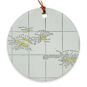 May include: A vintage map of the Azores islands, a group of volcanic islands in the North Atlantic Ocean, printed on a white ceramic ornament. The map shows the islands of Graciosa, Sao Jorge, Pico, Terceira, and Santo Miguel. The map is in yellow and brown colours.