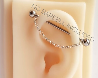 May include: A silver chain attached to a silver barbell piercing. The barbell is inserted into a fake earlobe. The text "NO BARBELL INCLUDED" is printed on the image.