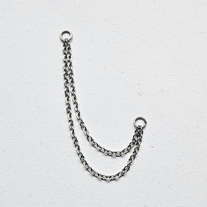 May include: Silver-coloured double chain earring with two small hoops. The chains are made of small, linked rings. The earring hangs on a white background.