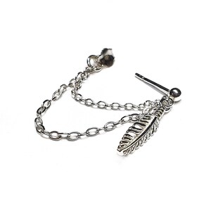 K&ouml;nnte beinhalten: Silberner Kettenohrring mit einem Federschmuck. Die Kette ist an einem Ohrstecker befestigt.