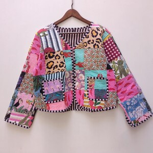 Può includere: Una giacca trapuntata a maniche lunghe con un design patchwork composto da vari motivi colorati, tra cui stampa leopardata, motivi floreali, righe e immagini tropicali. La giacca presenta uno scollo a V, chiusura frontale con bottoni e due tasche.