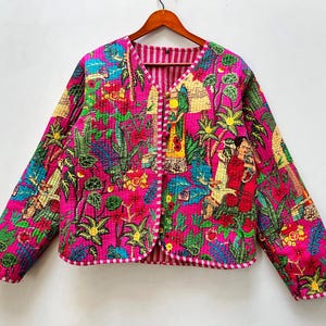 May include: A vibrant pink quilted jacket with a colorful floral and figure pattern. The jacket features a V-neck, long sleeves, and a striped trim. The design includes various plants and figures in shades of green, blue, yellow, and red.
