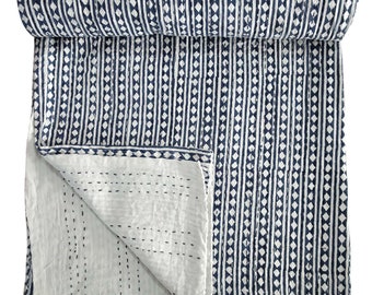 Könnte beinhalten: Eine weiße und blaue Kantha-Steppdecke mit geometrischem Muster. Die Decke ist in der Hälfte gefaltet und aufgerollt.
