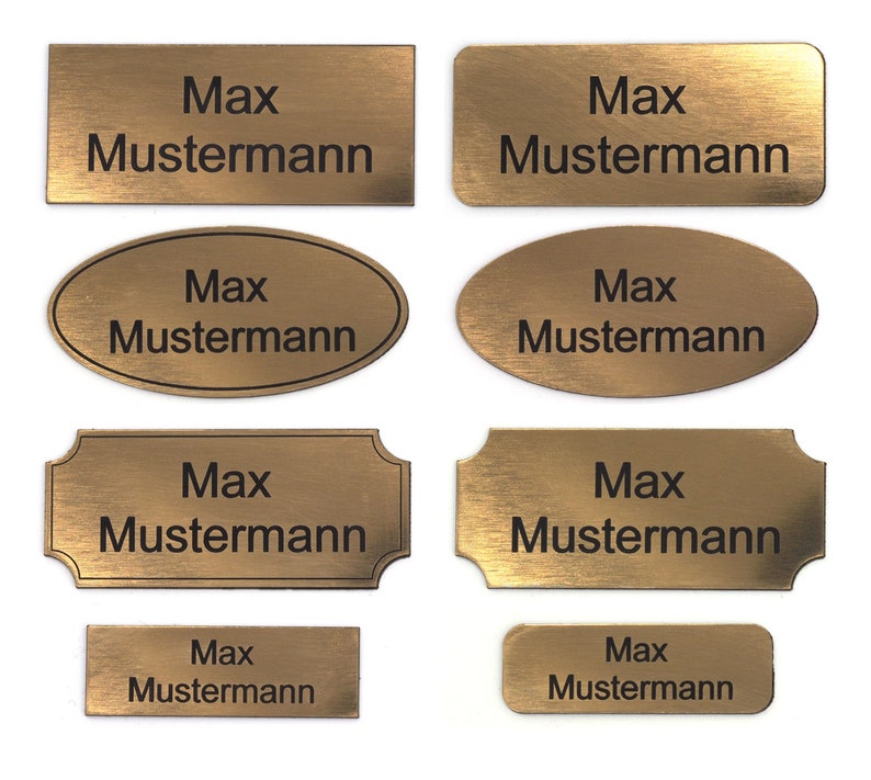 Puede incluir: Ocho placas de nombre de metal de color dorado con esquinas redondeadas y acabado cepillado. Las placas de nombre presentan el texto "Max Mustermann" en letras negras.