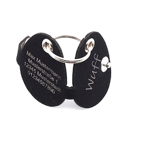 Könnte beinhalten: Schwarzes Leder-Hundeanhänger mit einem silbernen Ring. Eine Seite ist mit dem Text "Max Mustermann Musterstraße 1 12345 Musterstadt 01234567890" graviert. Die andere Seite ist mit dem Text "Wuff" graviert.