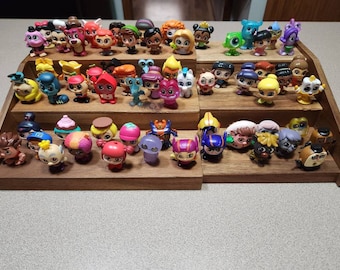 May include: A collection of small, colourful plastic figurines displayed on a wooden shelf. The figurines are various characters from popular children's movies and TV shows.