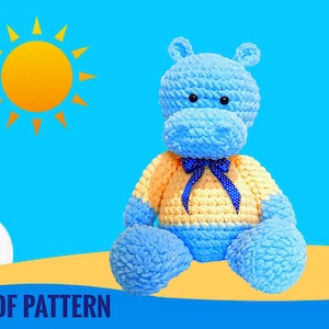 May include: A crocheted blue and yellow hippopotamus plush toy with a blue bow. The hippopotamus is sitting on a sandy beach with a blue sky and a yellow sun in the background. PDF PATTERN.