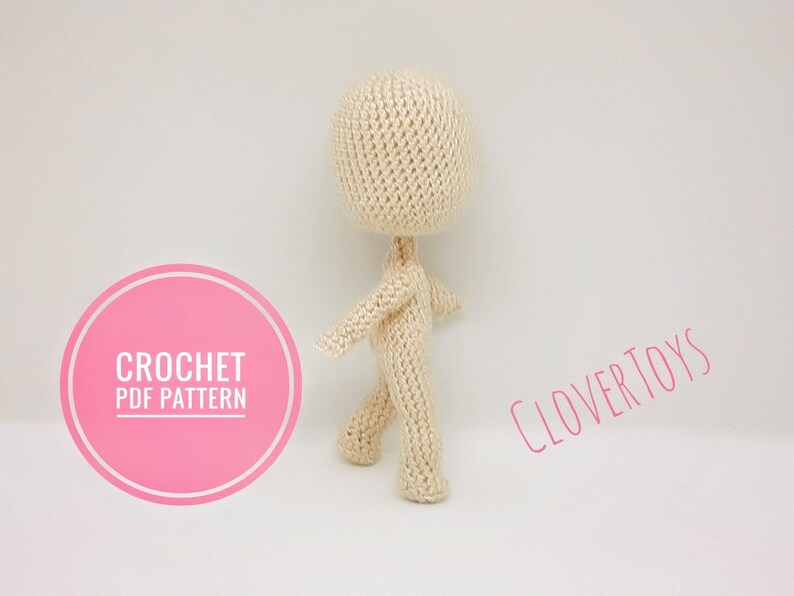 May include: Crochet PDF pattern for a beige amigurumi doll. The doll is standing with its arms outstretched and legs slightly apart. The pattern is available for download from Clover Toys.