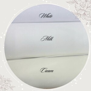 May include: A close-up of three fabric swatches in different shades of white. The swatches are labeled "White", "Milk", and "Cream".